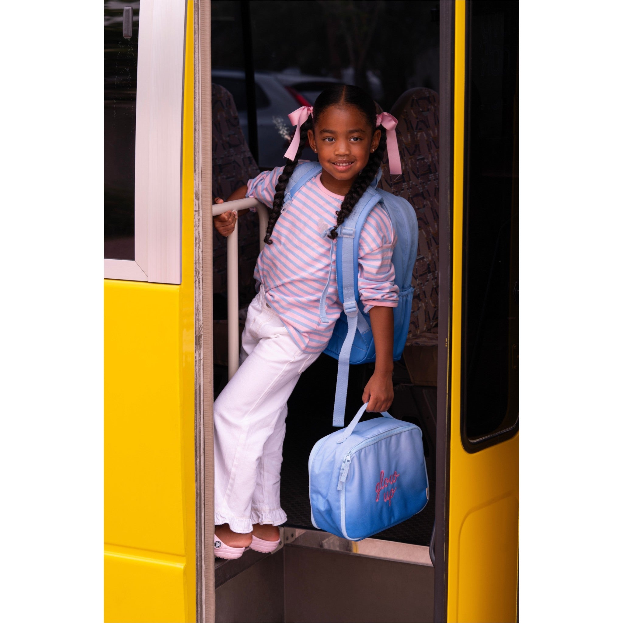 Young girl wearing Lil Bunnies - The Collective blue glowup grand backpack and carrying a matching lunch bag