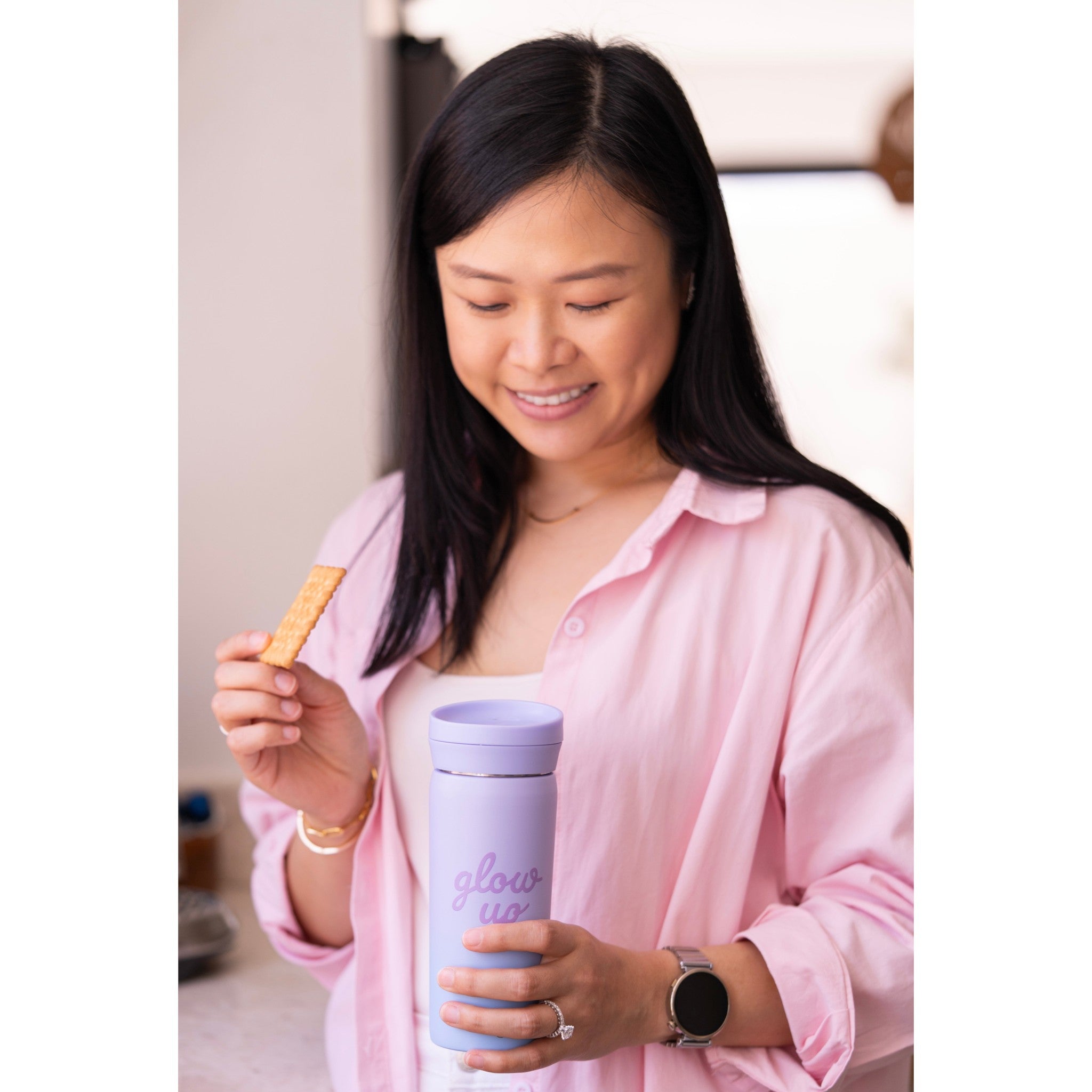 Woman in pink shirt holding a Lil Bunnies - The Collective 450ml purple blue Glowup coffee mug with a biscuit