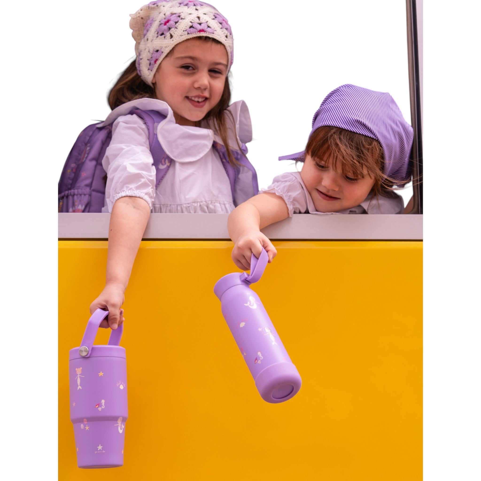 Two girls holding Lil Bunnies - The Collective 600ml purple insulated mermaid tumblers with carry handles