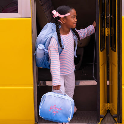 Lil Bunnies - The Collective blue insulated square lunch bag with glow up text held by a girl boarding a school bus