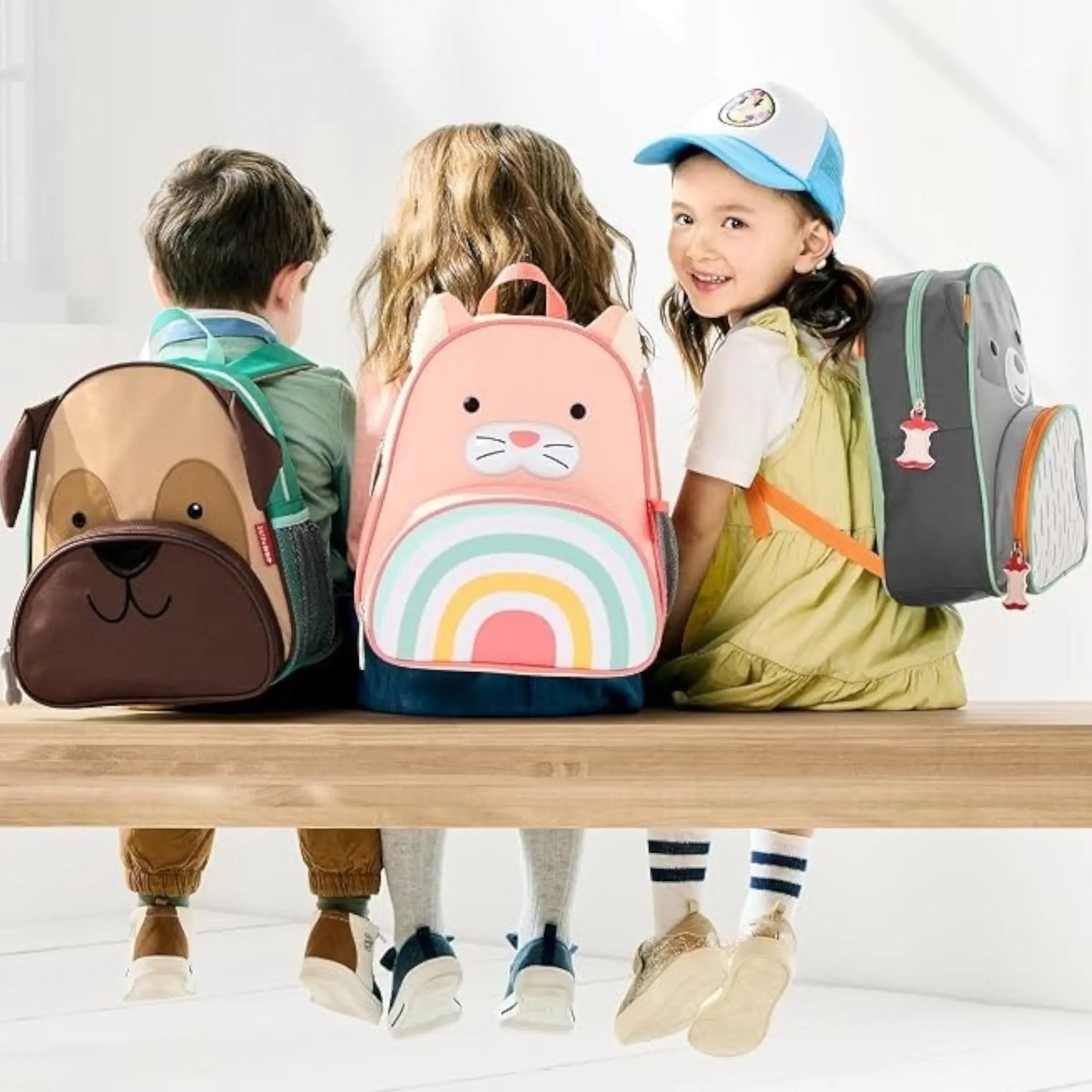 Lil Bunnies - The Collective cat zoo backpack with rainbow design worn by a child sitting on a bench with friends