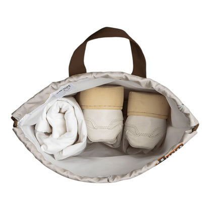 Lil Bunnies - The Collective drawstring wet bag featuring a vehicle print, holding white shoes and a folded cloth.