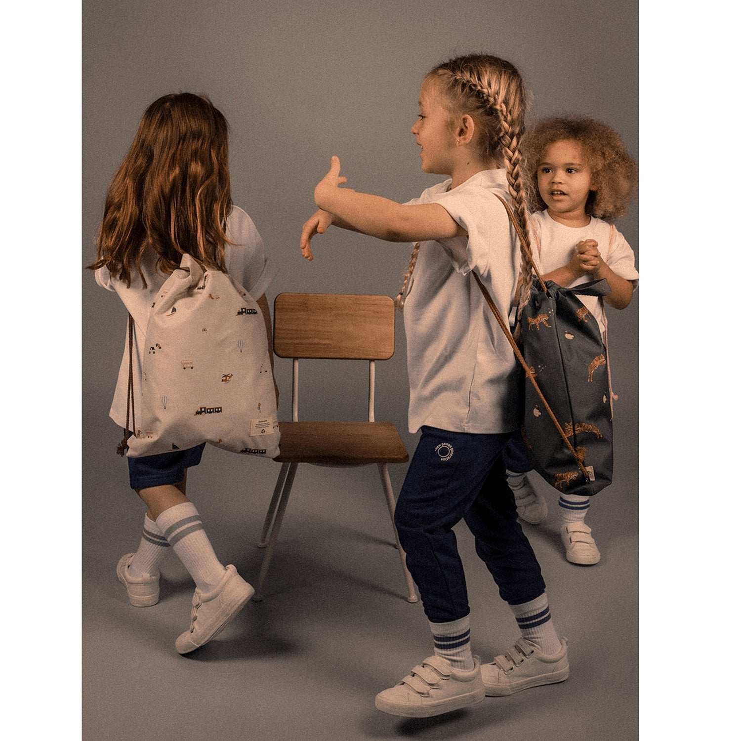 Lil Bunnies - The Collective drawstring wet bags with vehicle prints carried by children in a studio setting