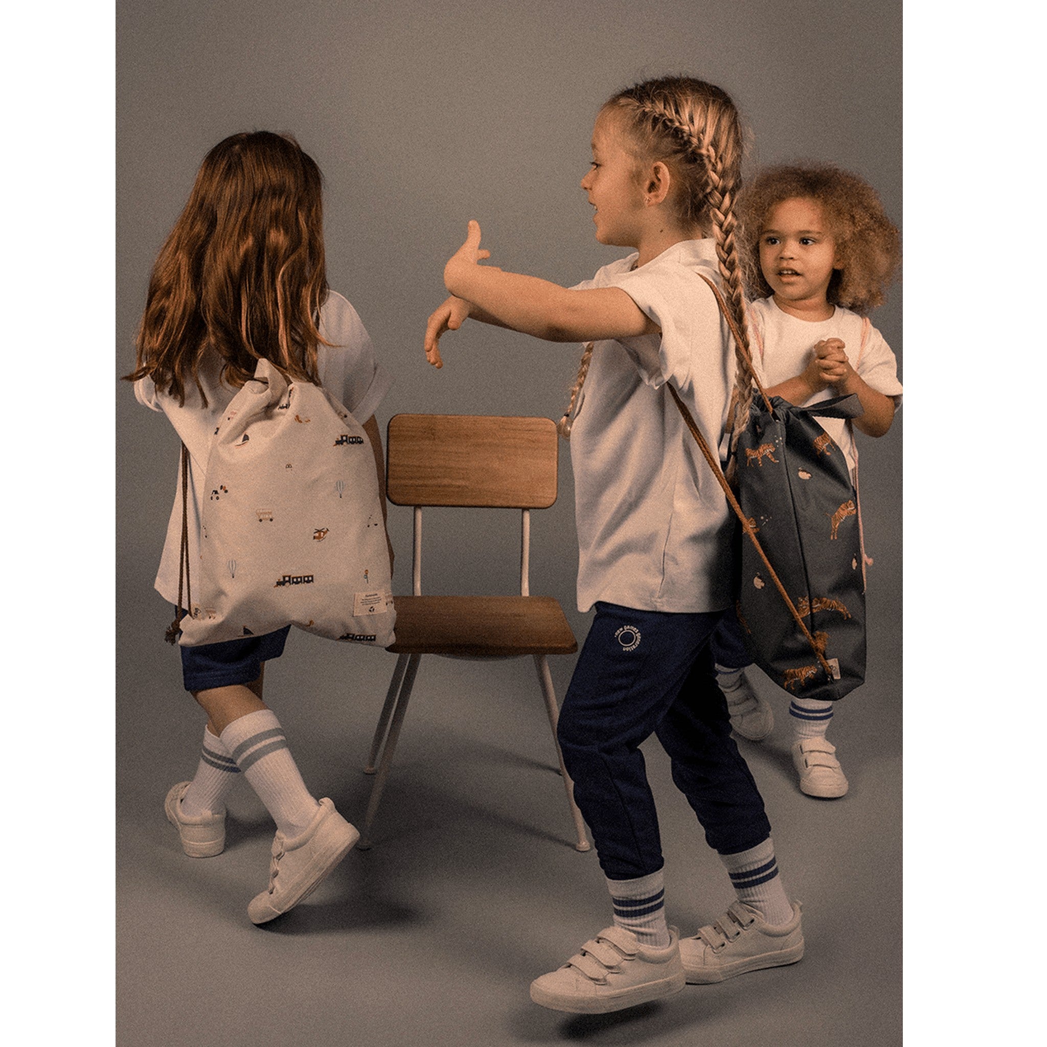 Lil Bunnies - The Collective drawstring wet bags with vehicle prints carried by children in a studio setting