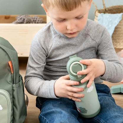 A young boy holding a green Lil Bunnies - The Collective insulated bottle with a cloud print while sitting on a floor