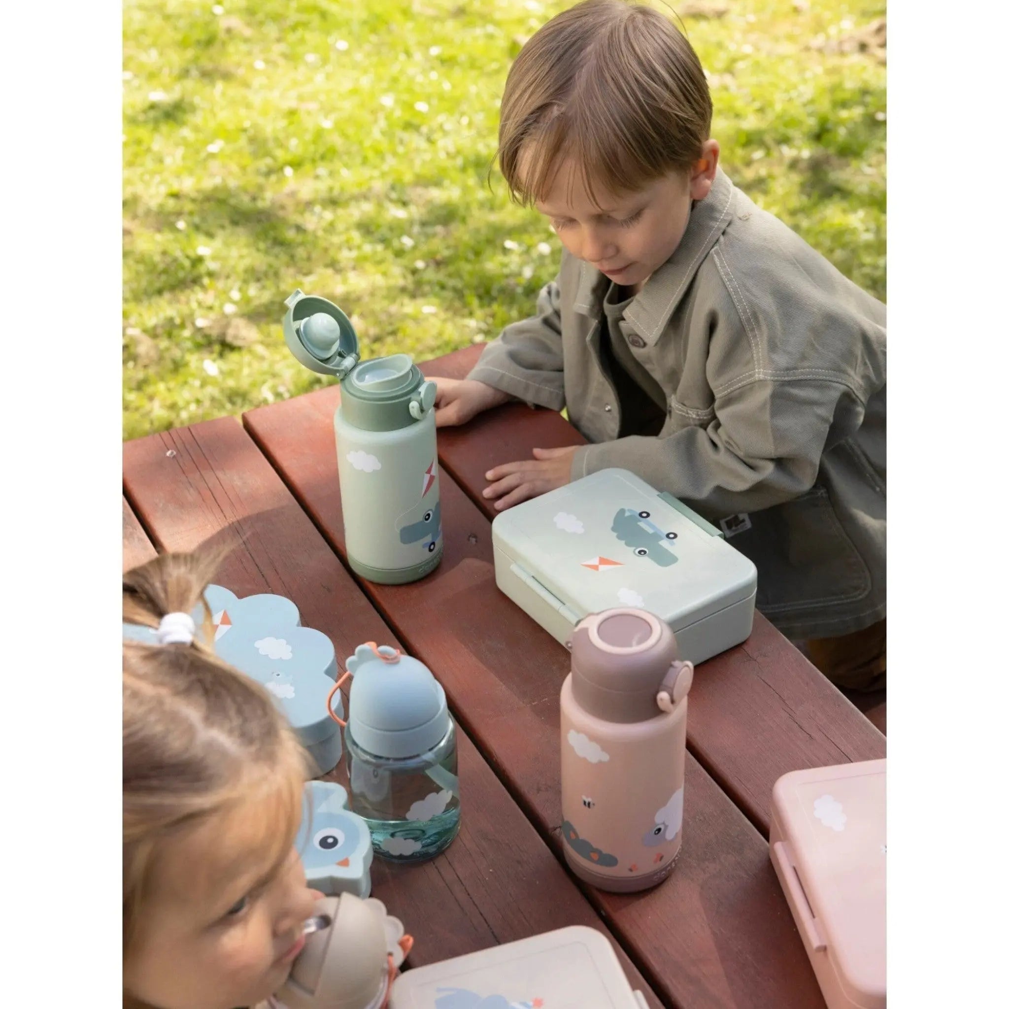 Lil Bunnies - The Collective green insulated bottle with car print on a picnic table with children