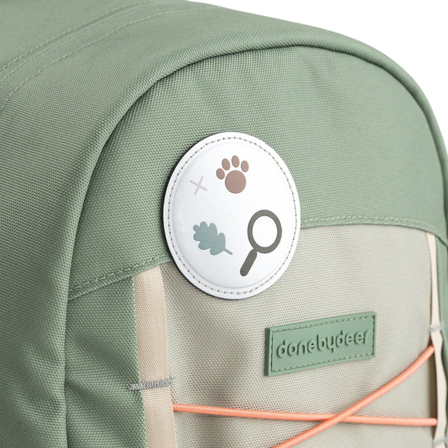 Lil Bunnies - The Collective Junior Backpack Tiny Trails in green with a nature-themed patch and orange bungee cord.