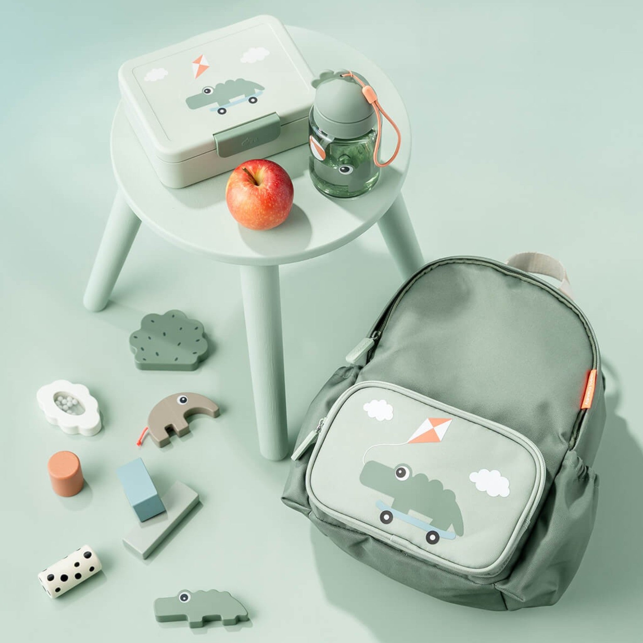 Lil Bunnies - The Collective green kids backpack with crocodile print next to a matching lunchbox and water bottle