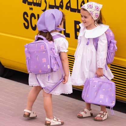 Two girls wearing Lil Bunnies - The Collective purple mermaid print insulated lunchbag backpacks and white dresses.