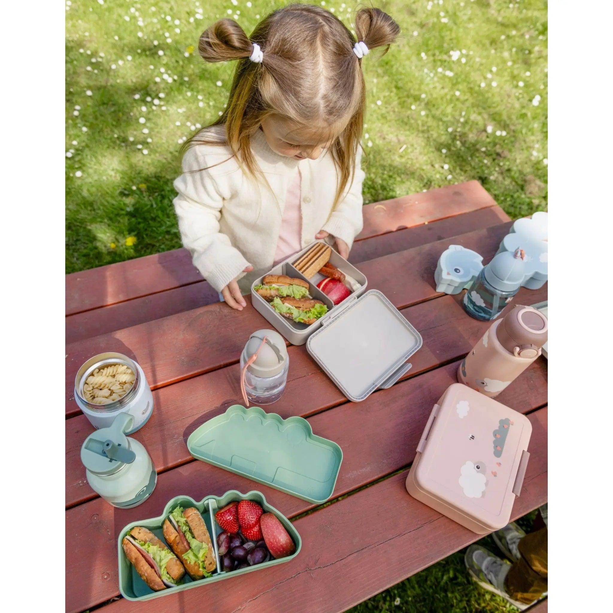 Lil Bunnies - The Collective sand-coloured lunch box with divider, open on a picnic table with a young girl