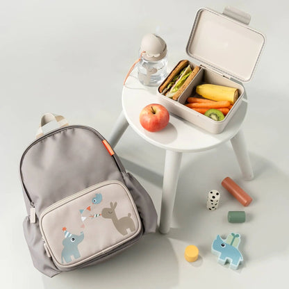 Lil Bunnies - The Collective sand-colored lunch box with divider, open and filled with a sandwich, banana, and kiwi.