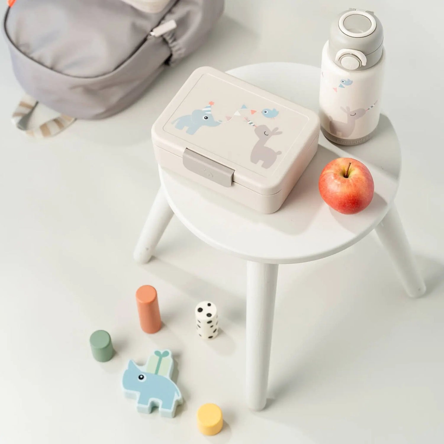 Lil Bunnies - The Collective sand-colored lunch box with divider and cute animal print on a white stool with bottle