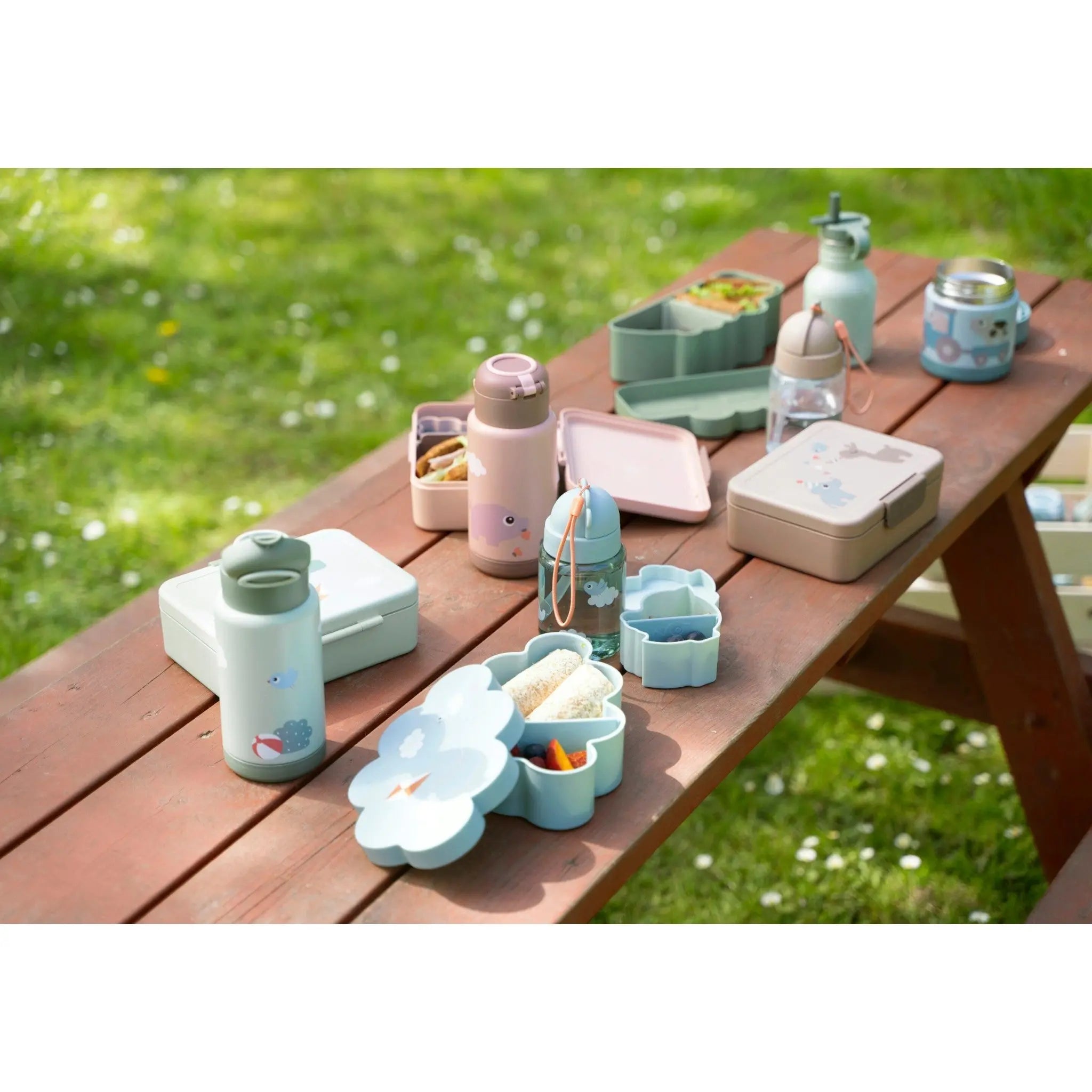 Lil Bunnies - The Collective sand coloured lunch box with divider displayed on a wooden picnic table with accessories