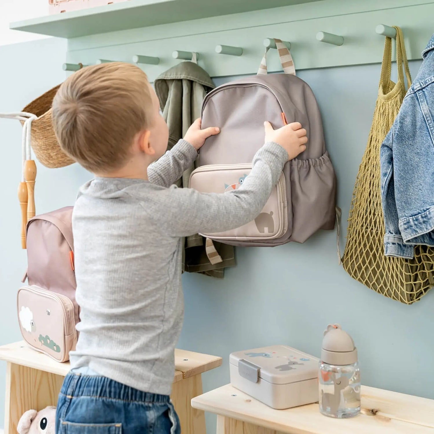 Lil Bunnies - The Collective sand coloured lunch box with divider on a wooden bench next to a matching backpack