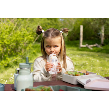 Lil Bunnies - The Collective sand-coloured lunch box with divider on a picnic table with a young girl drinking water
